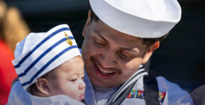 Navy sailor in uniform cradling a baby, with chapter title 'Chapter 12' and subtitle 'Decoding Civilian Compensation — Health care, co-pays, and 401ks'